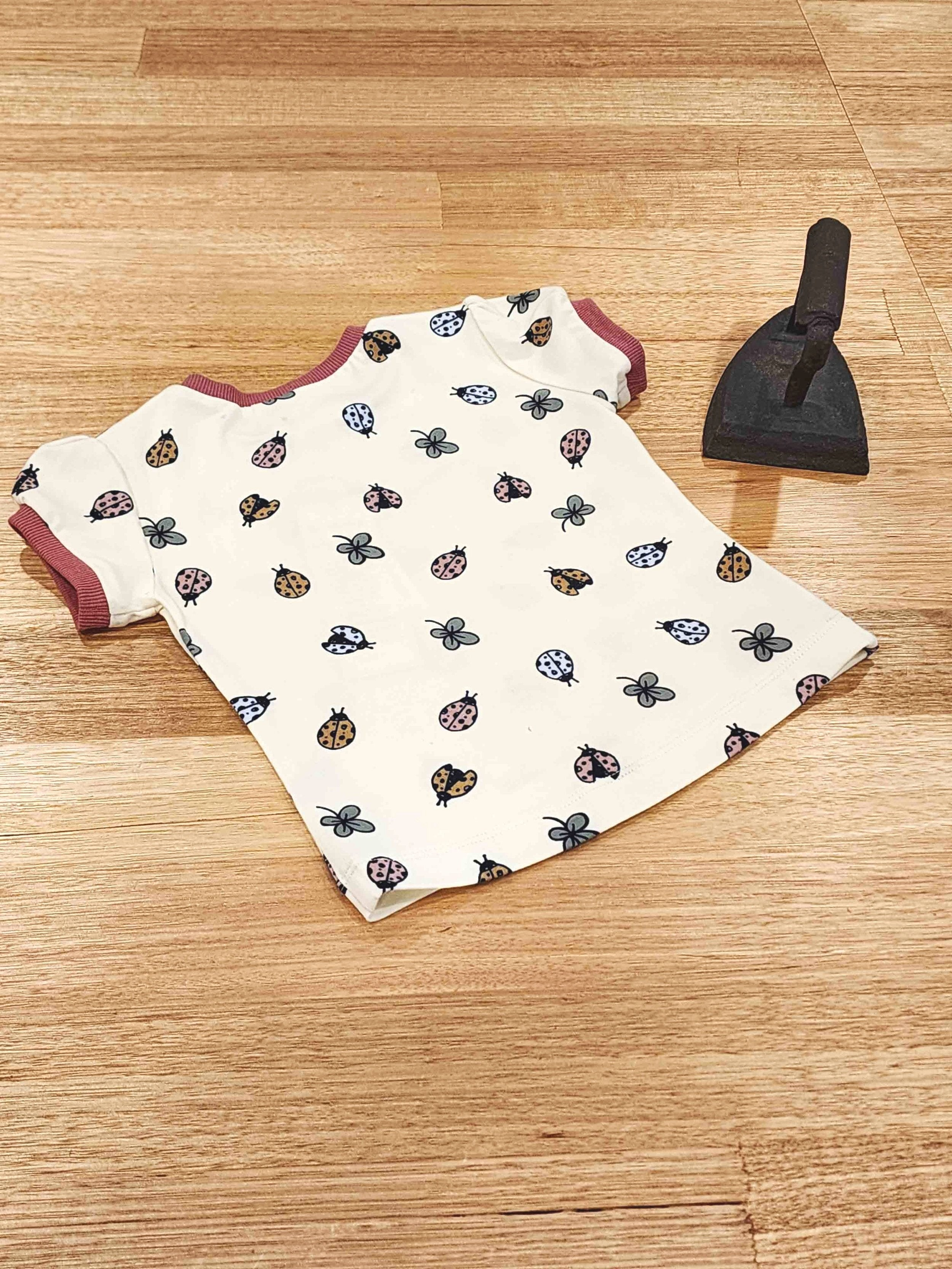 Flat Lay of new childrens collection showing a dress, tee shirt and bloomers in two colour ways, Owl and Quoll in white an Blue and Magnetic in bright multi colours featuring fuscia trim